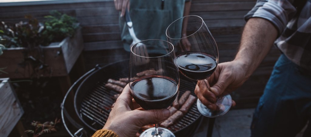 Anstoßen mit Rotwein neben dem Grill